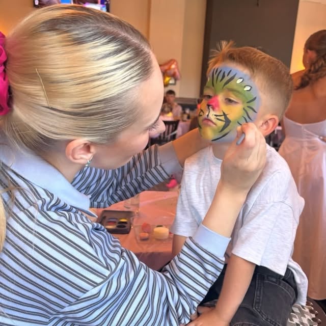 Ellie at work painting a bright tiger design at a children's celebration